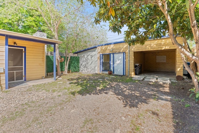 4611 Rosedale Ave, Austin, TX 78756 - rear view of house featuring a chimney, an outdoor structure, dirt driveway, and a carport