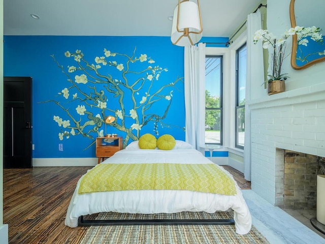 bedroom with wood finished floors, baseboards, and a fireplace