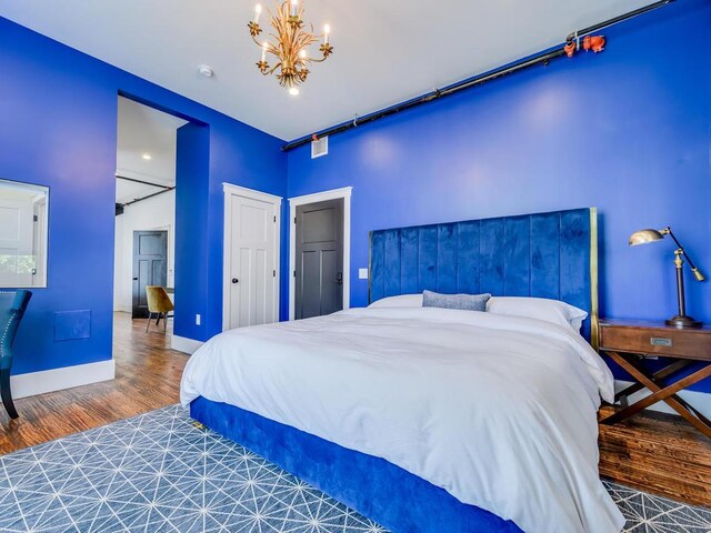 bedroom with wood finished floors, a chandelier, and baseboards