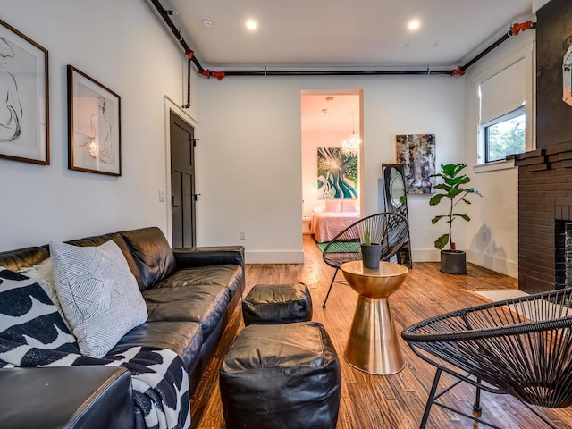 living area with wood finished floors, a brick fireplace, baseboards, and recessed lighting