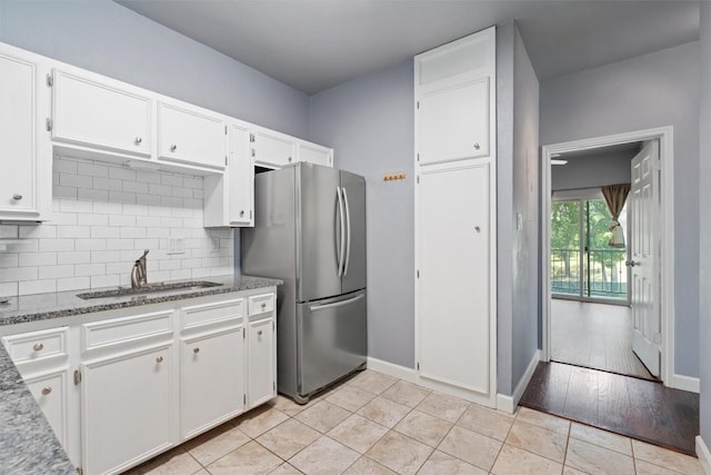 2414 Longview St Unit 303, Austin, TX 78705 - kitchen featuring freestanding refrigerator, white cabinets, decorative backsplash, and stone counters