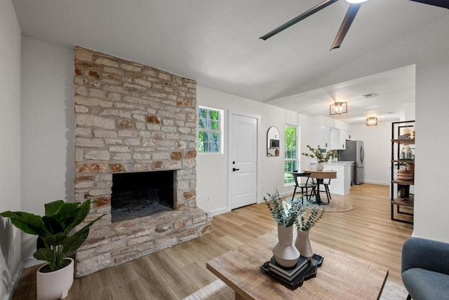 living room featuring lofted ceiling, a ceiling fan, light wood-type flooring, and a fireplace