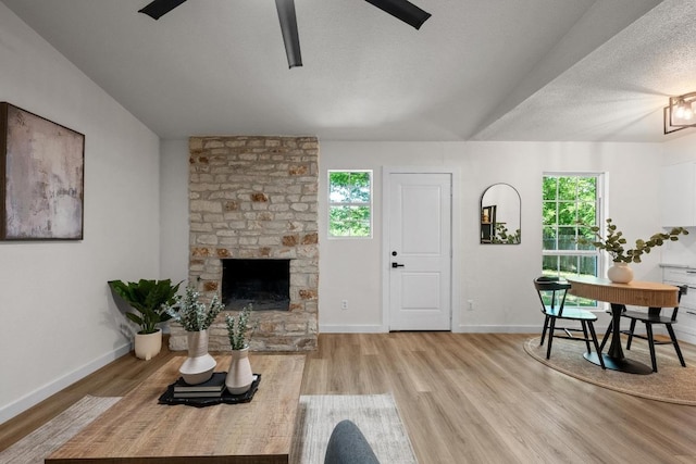 living room with plenty of natural light, a ceiling fan, a fireplace, baseboards, and a textured ceiling