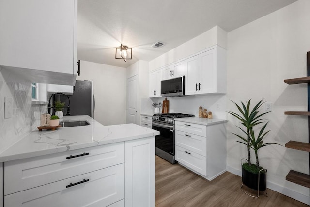 7002 Teaberry Dr, Austin, TX 78745 - kitchen with appliances with stainless steel finishes, white cabinetry, light wood-style flooring, and light stone countertops