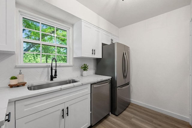 7002 Teaberry Dr, Austin, TX 78745 - kitchen with appliances with stainless steel finishes, white cabinetry, light wood finished floors, backsplash, and light stone countertops