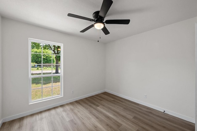 unfurnished room with wood finished floors, baseboards, and a ceiling fan