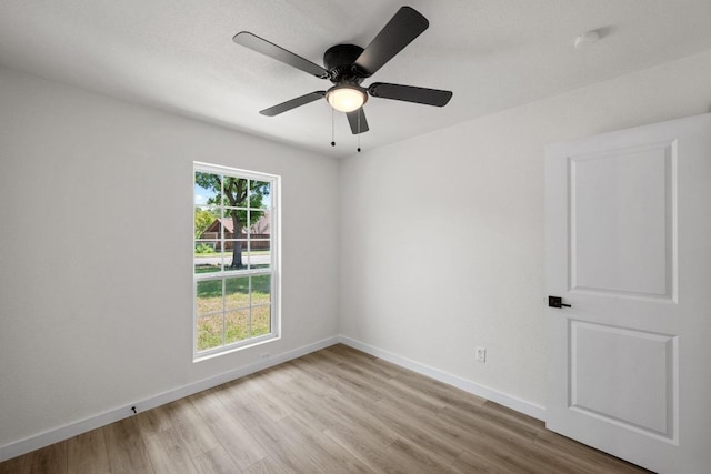 empty room with wood finished floors, baseboards, and a ceiling fan