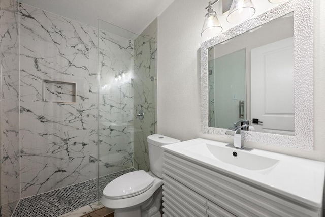 bathroom featuring toilet, a marble finish shower, vanity, and a textured wall