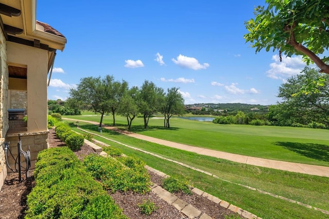 view of property's community with view of golf course, a water view, and a yard