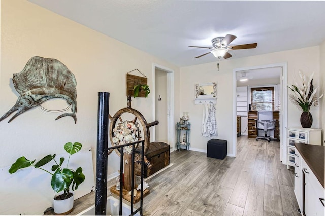 foyer entrance featuring light wood-style floors, a ceiling fan, and baseboards