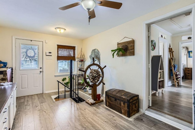 foyer with light wood-style flooring, ceiling fan, crown molding, and baseboards