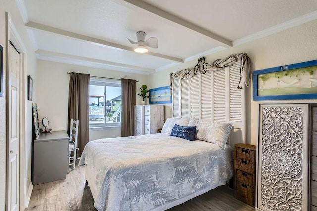 bedroom with beamed ceiling, wood finished floors, a ceiling fan, and ornamental molding