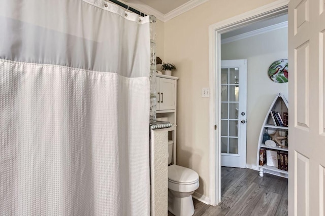 bathroom with ornamental molding, wood finished floors, toilet, baseboards, and a shower with shower curtain