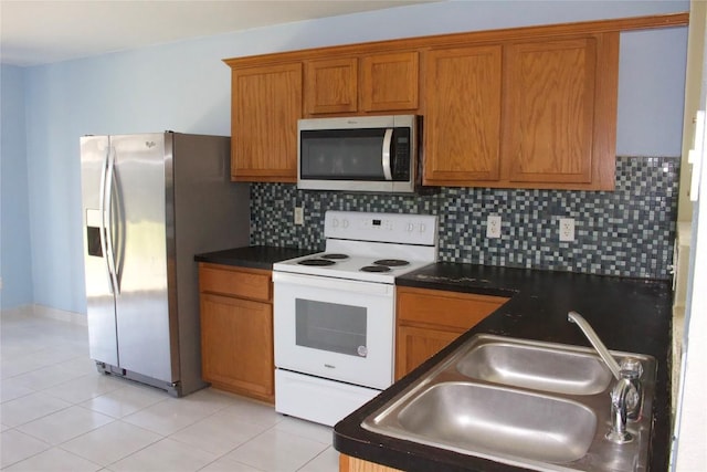 kitchen with stainless steel appliances, a sink, dark countertops, and brown cabinetry