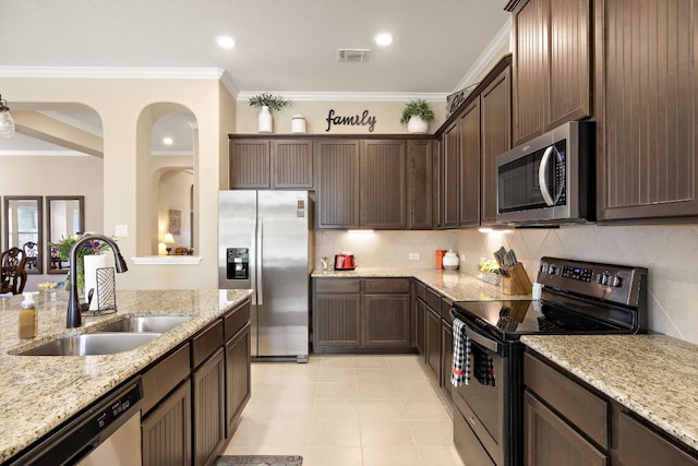 417 Freeman Park Pl, Round Rock, TX 78665 - kitchen with stainless steel appliances, a sink, dark brown cabinets, tasteful backsplash, and ornamental molding