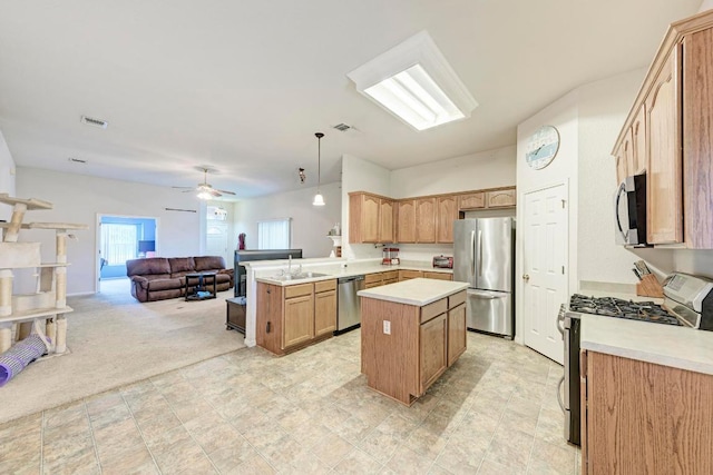 kitchen featuring appliances with stainless steel finishes, open floor plan, light countertops, a center island, and a peninsula