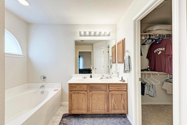 full bathroom with a bath, double vanity, baseboards, and a spacious closet