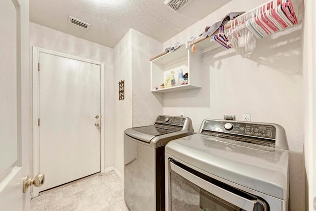 washroom with washing machine and dryer and a textured ceiling