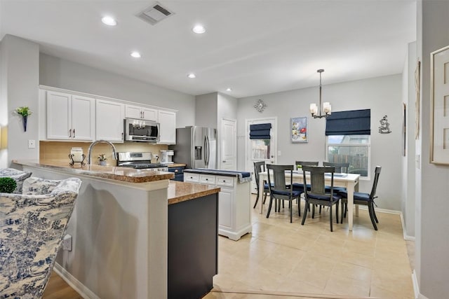 360 Waterloo Dr, Kyle, TX 78640 - kitchen featuring appliances with stainless steel finishes, a chandelier, white cabinetry, a peninsula, and recessed lighting