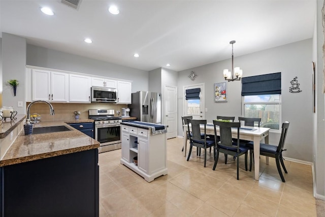 360 Waterloo Dr, Kyle, TX 78640 - kitchen with stainless steel appliances, a sink, white cabinets, a center island, and a chandelier