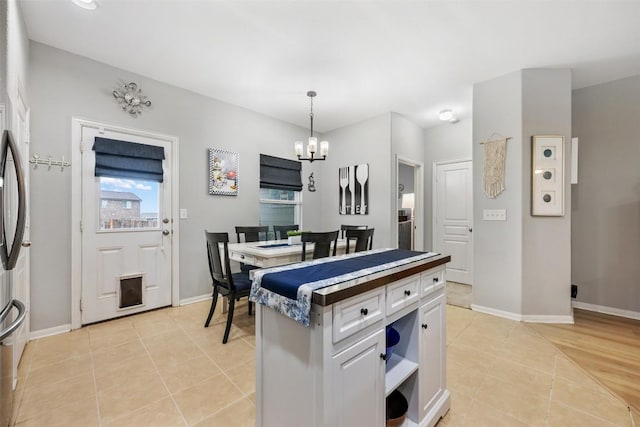 360 Waterloo Dr, Kyle, TX 78640 - kitchen featuring a chandelier, light tile patterned floors, hanging light fixtures, baseboards, and white cabinets