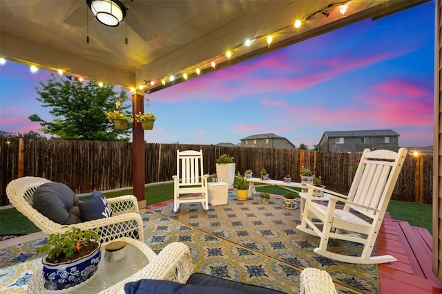 patio terrace at dusk with ceiling fan, a fenced backyard, and outdoor dining area