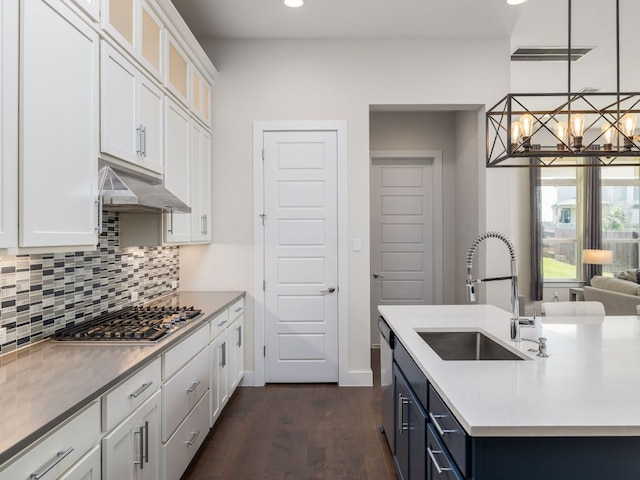 20513 Christie Marie Ln, Pflugerville, TX 78660 - kitchen with a sink, under cabinet range hood, stainless steel gas cooktop, dark wood-style floors, and decorative backsplash