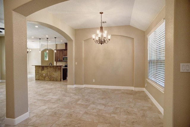 unfurnished dining area featuring a chandelier, arched walkways, healthy amount of natural light, vaulted ceiling, and baseboards