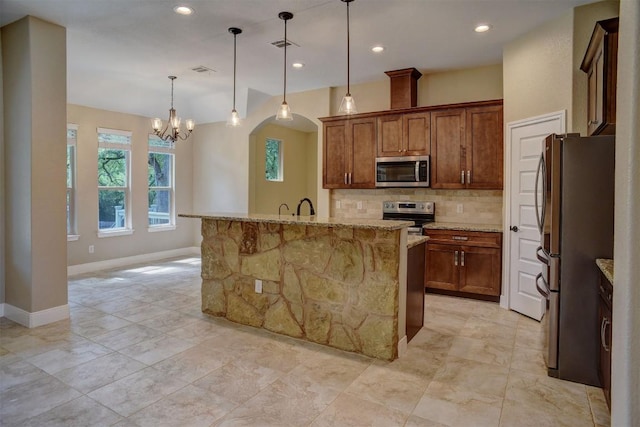 kitchen with stainless steel appliances, backsplash, baseboards, light stone counters, and a chandelier