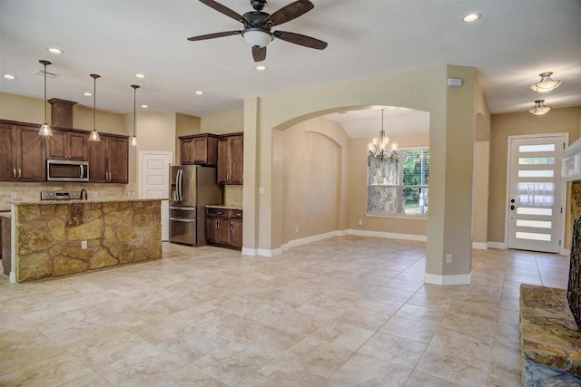 kitchen with appliances with stainless steel finishes, arched walkways, backsplash, a ceiling fan, and pendant lighting
