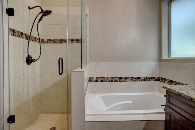 full bath featuring a shower stall, a bath, vanity, and a textured wall