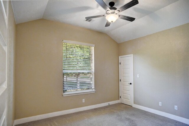 carpeted spare room with vaulted ceiling, ceiling fan, and baseboards