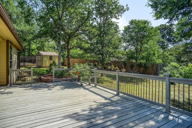 wooden deck featuring a storage shed, a fenced backyard, and an outdoor structure
