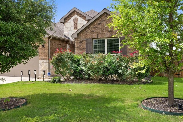 7404 Leonardo Dr, Round Rock, TX 78665 - view of front facade with brick siding, a shingled roof, a front yard, a garage, and stone siding