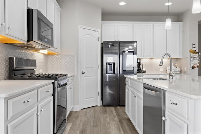 kitchen featuring stainless steel appliances, a sink, light wood finished floors, white cabinets, and recessed lighting