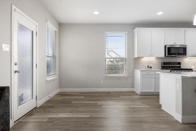 kitchen with appliances with stainless steel finishes, white cabinetry, light wood-style floors, light countertops, and recessed lighting