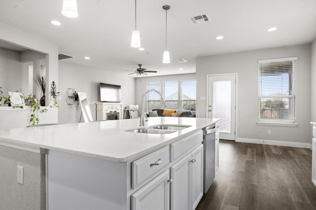 kitchen with a sink, stainless steel dishwasher, dark wood-type flooring, light countertops, and recessed lighting