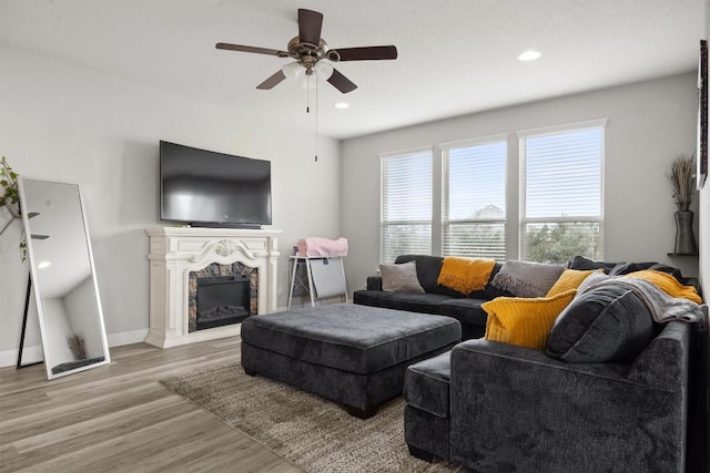 living room with a ceiling fan, wood finished floors, a fireplace, recessed lighting, and baseboards