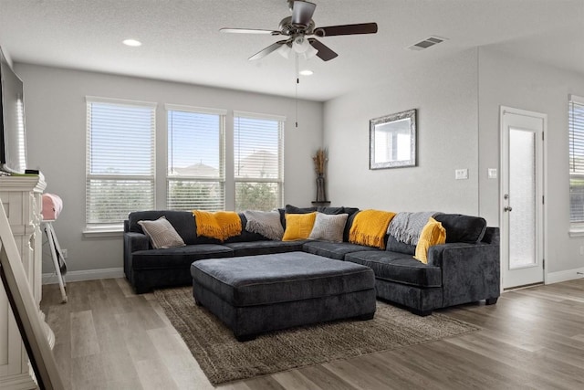 living area featuring baseboards, light wood-style flooring, a ceiling fan, and recessed lighting