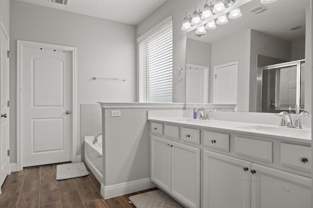 full bath with a stall shower, double vanity, wood finished floors, a bath, and baseboards