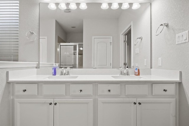 bathroom featuring a shower stall, double vanity, and a textured wall