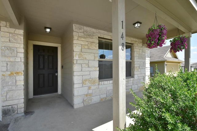 entrance to property with stone siding and a porch
