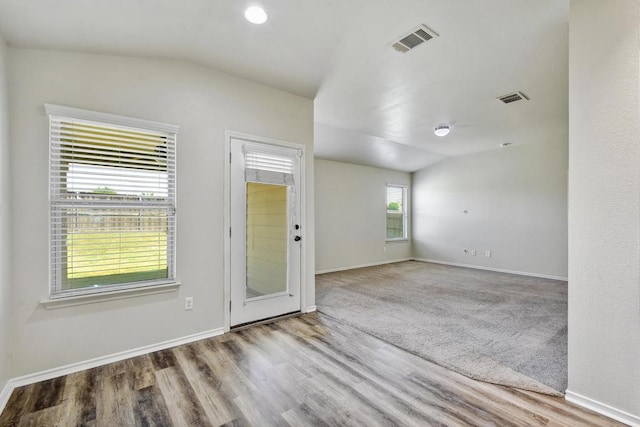unfurnished room featuring lofted ceiling, baseboards, and wood finished floors