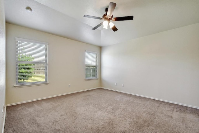 empty room with carpet floors, a ceiling fan, and baseboards