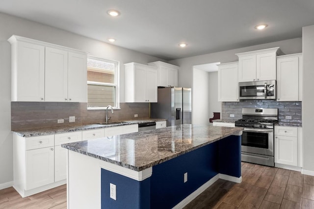 257 Falling Star Ln, Georgetown, TX 78628 - kitchen with appliances with stainless steel finishes, a sink, wood finished floors, tasteful backsplash, and dark stone countertops
