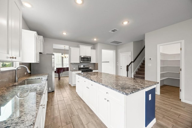 257 Falling Star Ln, Georgetown, TX 78628 - kitchen with stainless steel appliances, a sink, light wood-style flooring, a center island, and backsplash