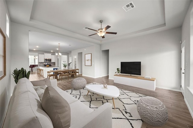 257 Falling Star Ln, Georgetown, TX 78628 - living room with a tray ceiling, wood finished floors, and baseboards