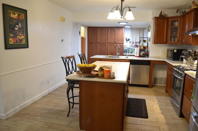 907 Pepperell Ct, Austin, TX 78753 - kitchen with appliances with stainless steel finishes, a sink, a breakfast bar, light wood finished floors, and light countertops