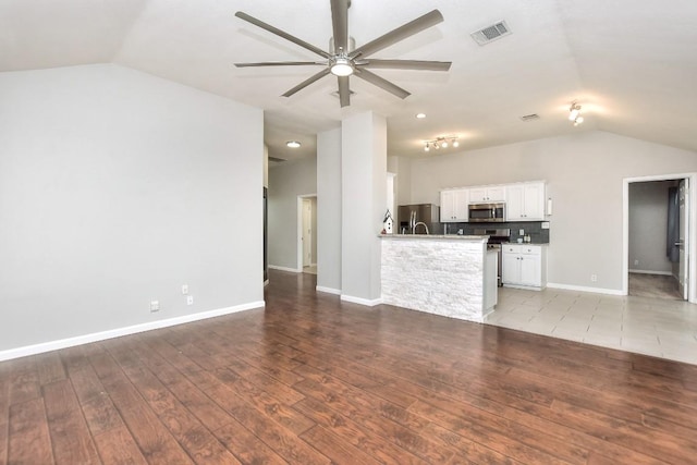 unfurnished living room featuring lofted ceiling, a ceiling fan, light wood-type flooring, and baseboards