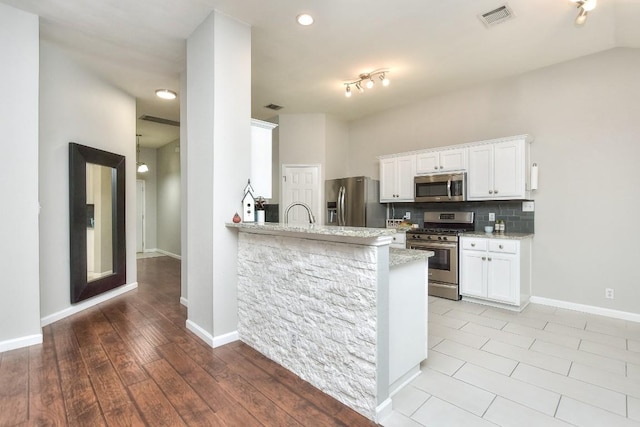 kitchen featuring appliances with stainless steel finishes, white cabinets, light stone countertops, tasteful backsplash, and recessed lighting